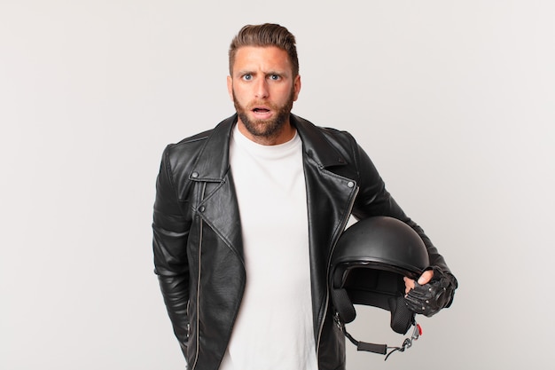 Young handsome man looking very shocked or surprised. motorbike helmet concept