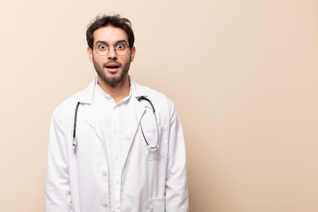 Young handsome man looking very shocked or surprised, staring with open mouth saying wow