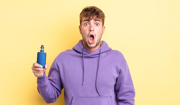 Young handsome man looking very shocked or surprised. vaporizer concept