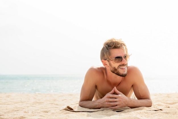 Young handsome man lying at the beach on summer vacations