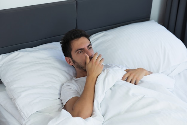 Young handsome man lying in his bed. The man is yawning and stretching.