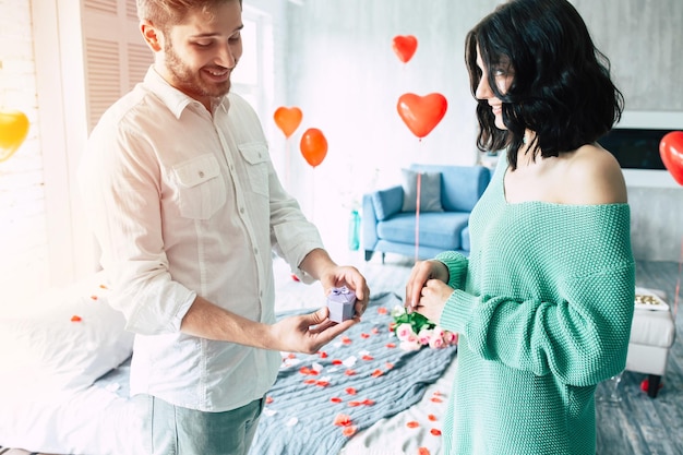 Young handsome man makes a proposal to his beautiful girlfriend to marry him in a beautiful bedroom with a romantic background. Husband and wife