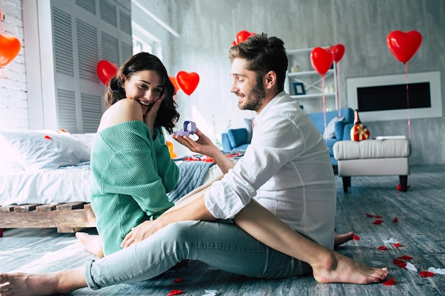 Young handsome man makes a proposal to his beautiful girlfriend to marry him in a beautiful bedroom with a romantic background. Husband and wife