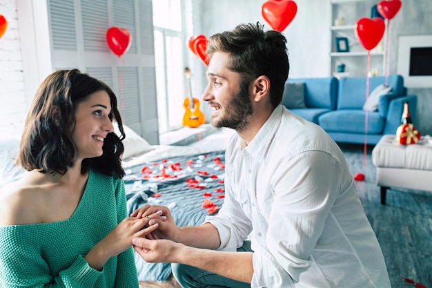 Young handsome man makes a proposal to his beautiful girlfriend to marry him in a beautiful bedroom with a romantic background. Husband and wife