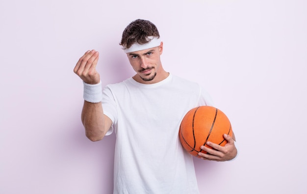 Young handsome man making capice or money gesture, telling you\
to pay. basketball concept