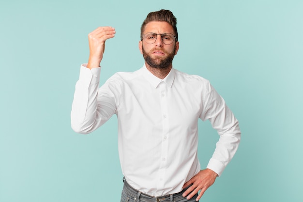 Young handsome man making capice or money gesture, telling you to pay