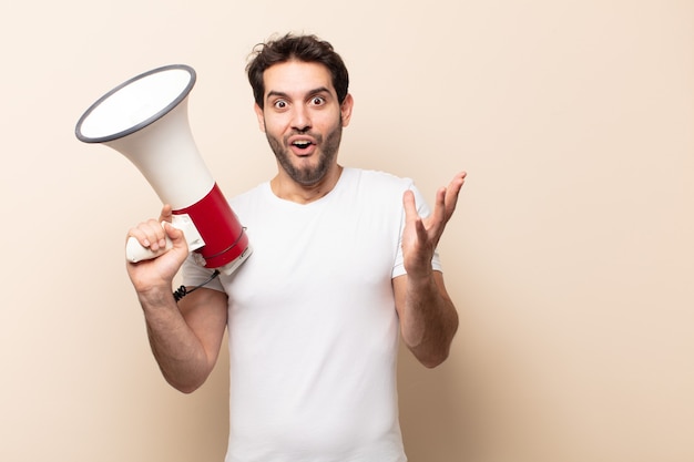 young handsome man open-mouthed and amazed, shocked and astonished with an unbelievable surprise