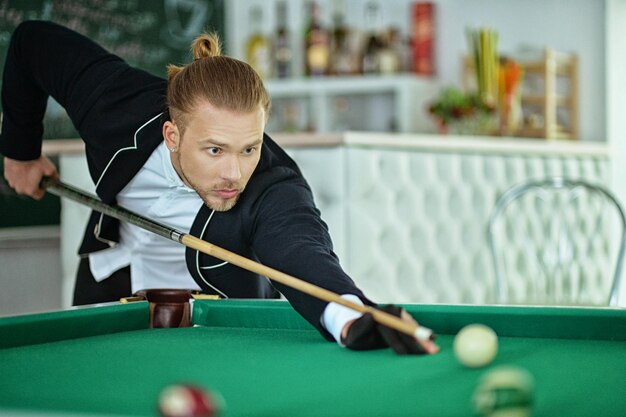 Young handsome man playing billiard in billiard club