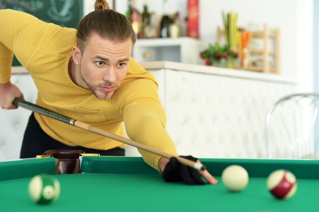 Young handsome man playing billiards in billiard club