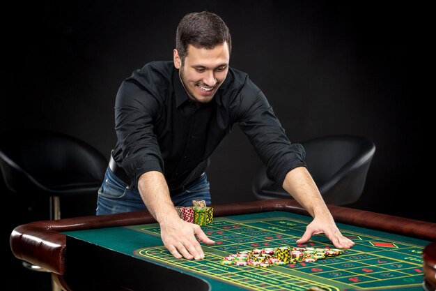 Foto il giovane uomo bello che gioca alla roulette vince al casinò