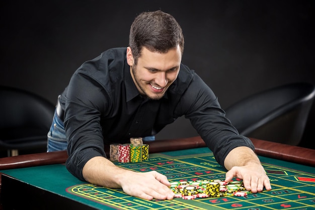 Young handsome man playing roulette wins at the casino