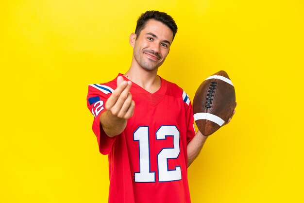 Young handsome man playing rugby over isolated yellow\
background making money gesture