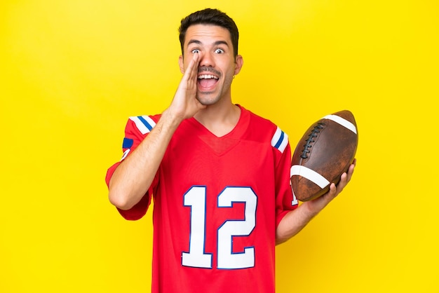 Young handsome man playing rugby over isolated yellow background shouting with mouth wide open