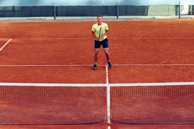 Young handsome man playing tennis on the tennis court