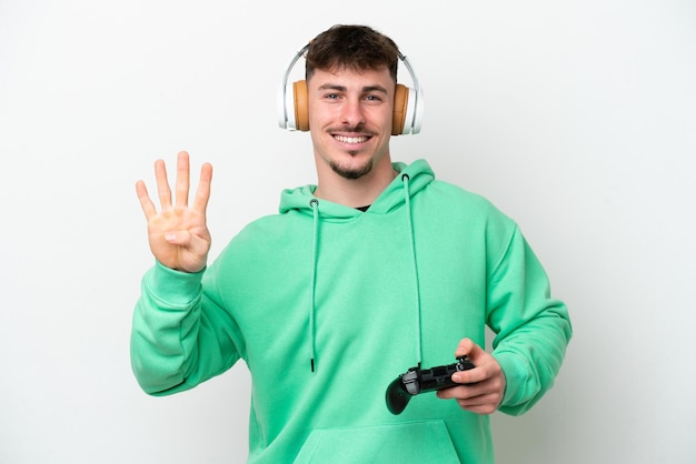 白い背景に分離されたビデオ ゲーム コントローラーで遊んで幸せと指で 4 つを数える若いハンサムな男