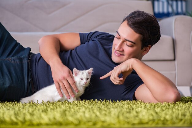 Young handsome man playing with white kitten