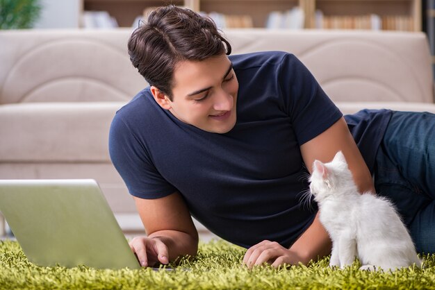 Young handsome man playing with white kitten