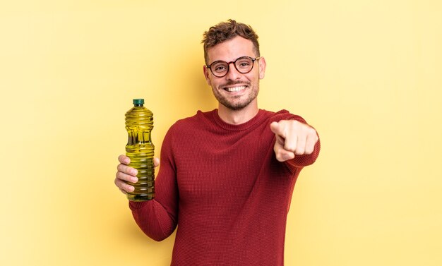 Young handsome man pointing at camera choosing you. olive oil concept