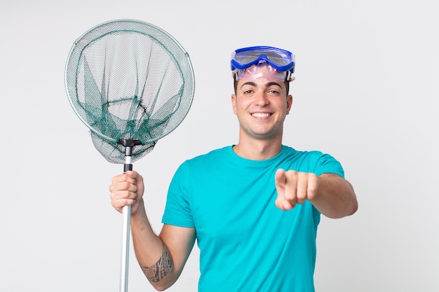 Young handsome man pointing at camera choosing you with goggles and fishing net