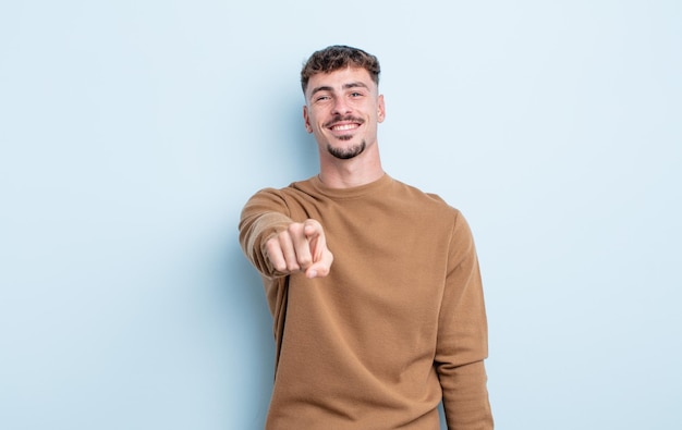 Foto giovane bell'uomo che punta alla telecamera con un sorriso soddisfatto, fiducioso e amichevole, scegliendo te