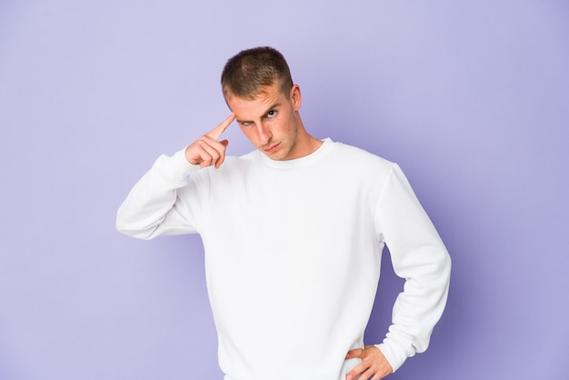 Young handsome man pointing temple with finger, thinking, focused on a task