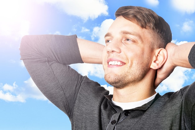 Foto giovane uomo bello in posa contro il cielo blu