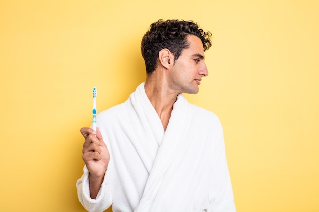 Young handsome man on profile view thinking, imagining or daydreaming. bathrobe and toothbrush concept