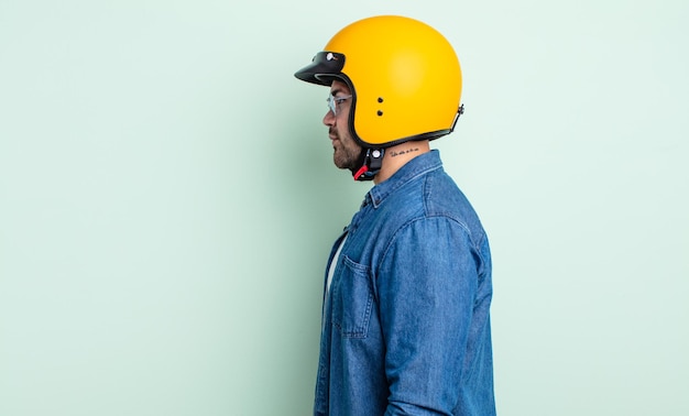 Young handsome man on profile view thinking, imagining or daydreaming. motorbike helmet concept