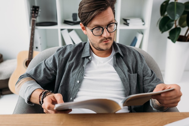 Young handsome man reading magazine