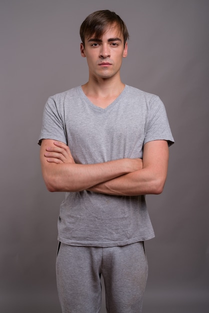 Young handsome man ready for gym against gray background