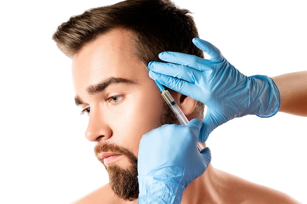 Молодой и красивый мужчина получает инъекции в кожу головы для роста волос