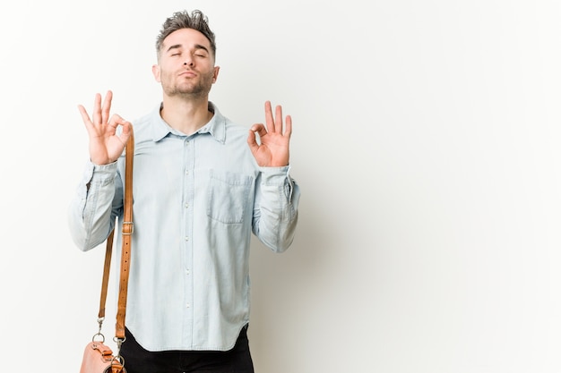 Il giovane uomo bello si rilassa dopo una dura giornata di lavoro, sta eseguendo yoga.