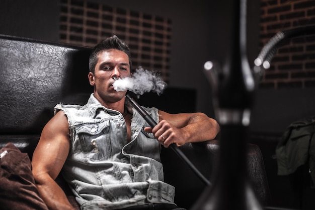 Young handsome man relaxes in a hookah at arabic restaurant The pleasure of smoking