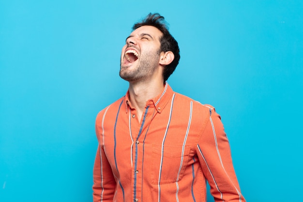 Young handsome man screaming furiously, shouting aggressively, looking stressed and angry