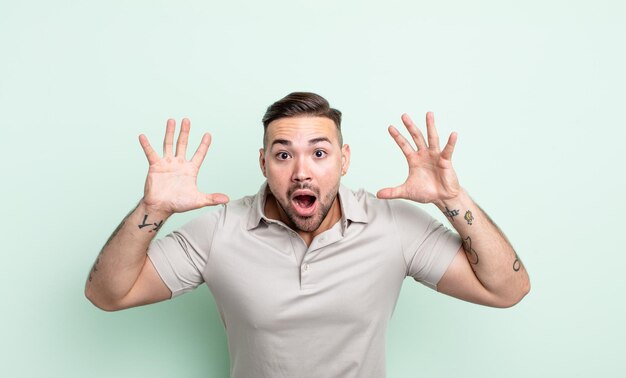 Young handsome man screaming with hands up in the air, feeling furious, frustrated, stressed and upset