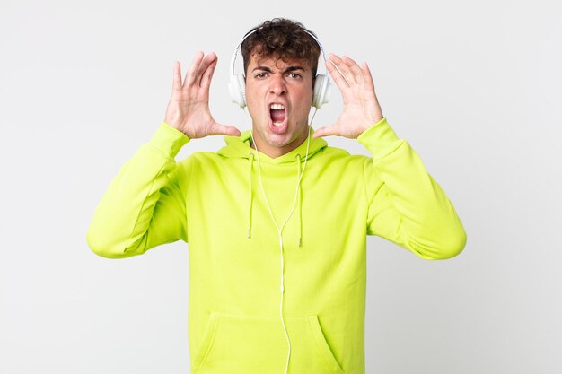 Young handsome man screaming with hands up in the air and headphones