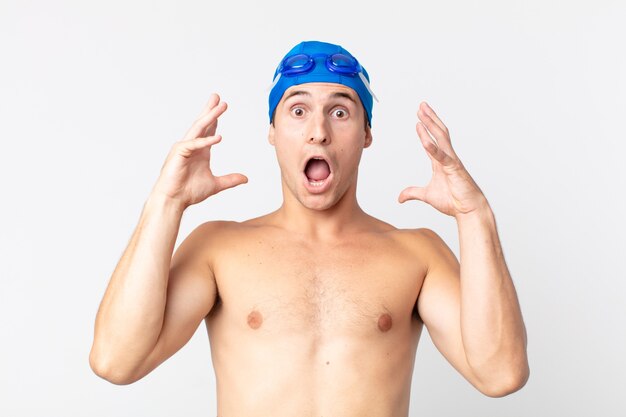 Young handsome man screaming with hands up in the air. swimmer concept