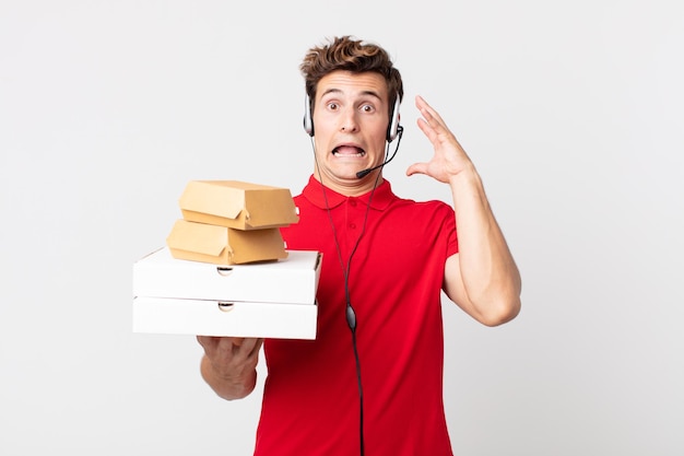 Young handsome man screaming with hands up in the air. take away fast food concept