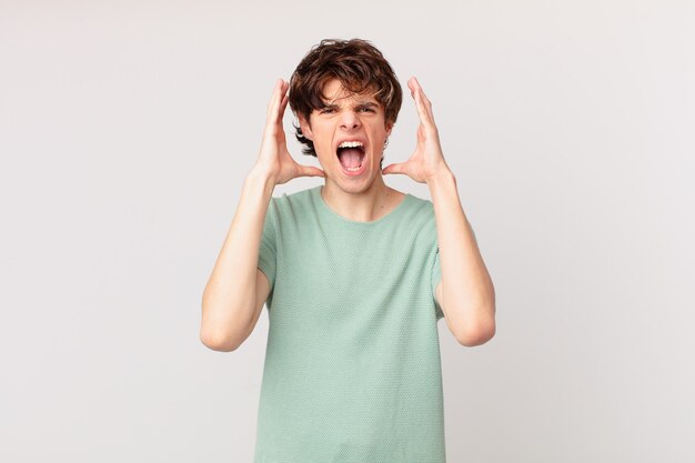 Young handsome man screaming with hands up in the air