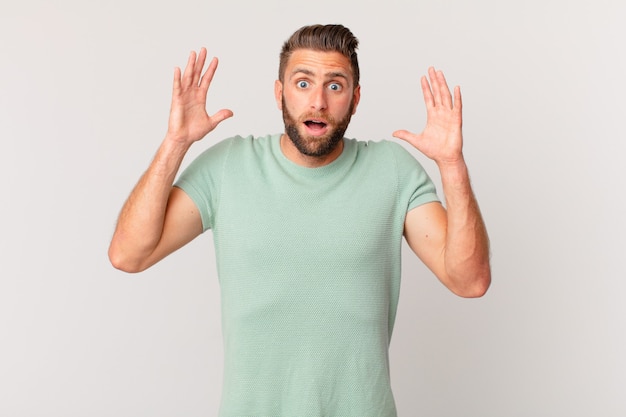 Young handsome man screaming with hands up in the air