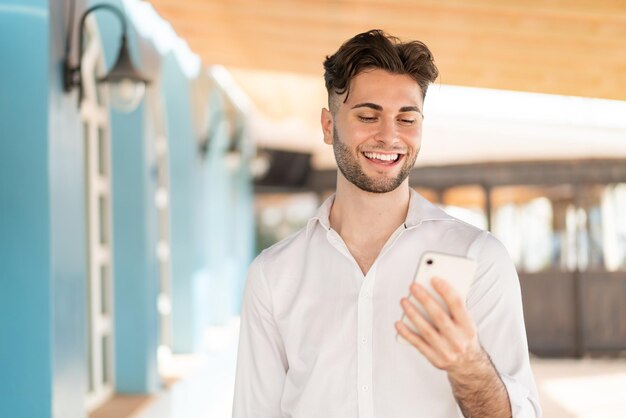 Young handsome man sending a message or email with the mobile