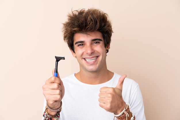 Young handsome man shaving his beard with thumbs up because something good has happened