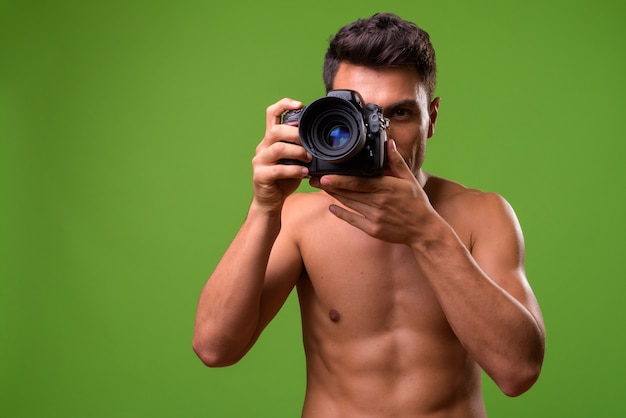 Young handsome man shirtless against green 