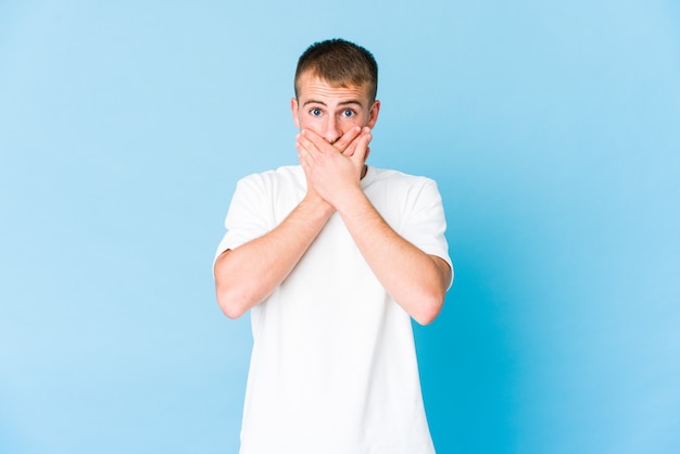 Young handsome man shocked covering mouth with hands