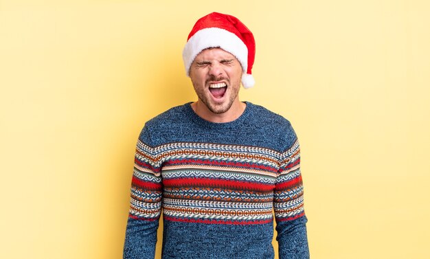 young handsome man shouting aggressively, looking very angry. christmas concept