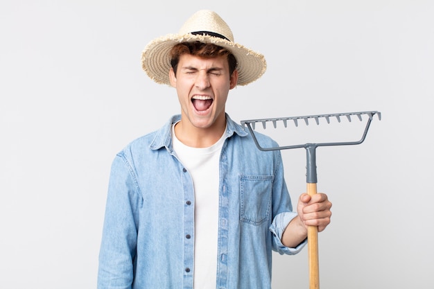 Young handsome man shouting aggressively, looking very angry. farmer concept