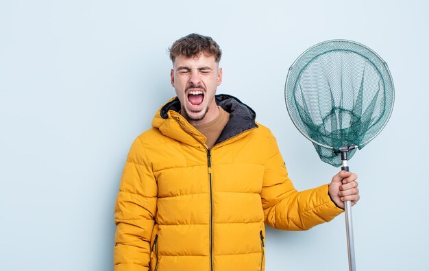 Young handsome man shouting aggressively, looking very angry. fisherman concept