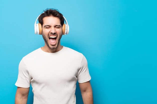 Young handsome man shouting aggressively, looking very angry, frustrated, outraged or annoyed, screaming no