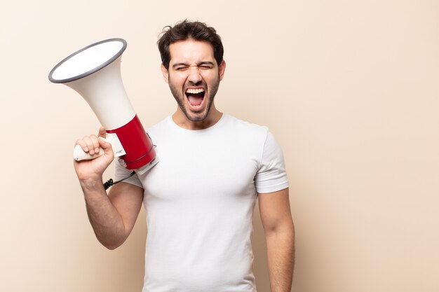 young handsome man shouting aggressively, looking very angry, frustrated, outraged or annoyed, screaming no