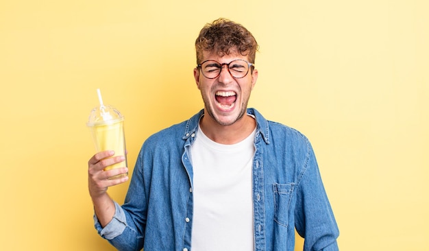 young handsome man shouting aggressively looking very angry milkshake concept